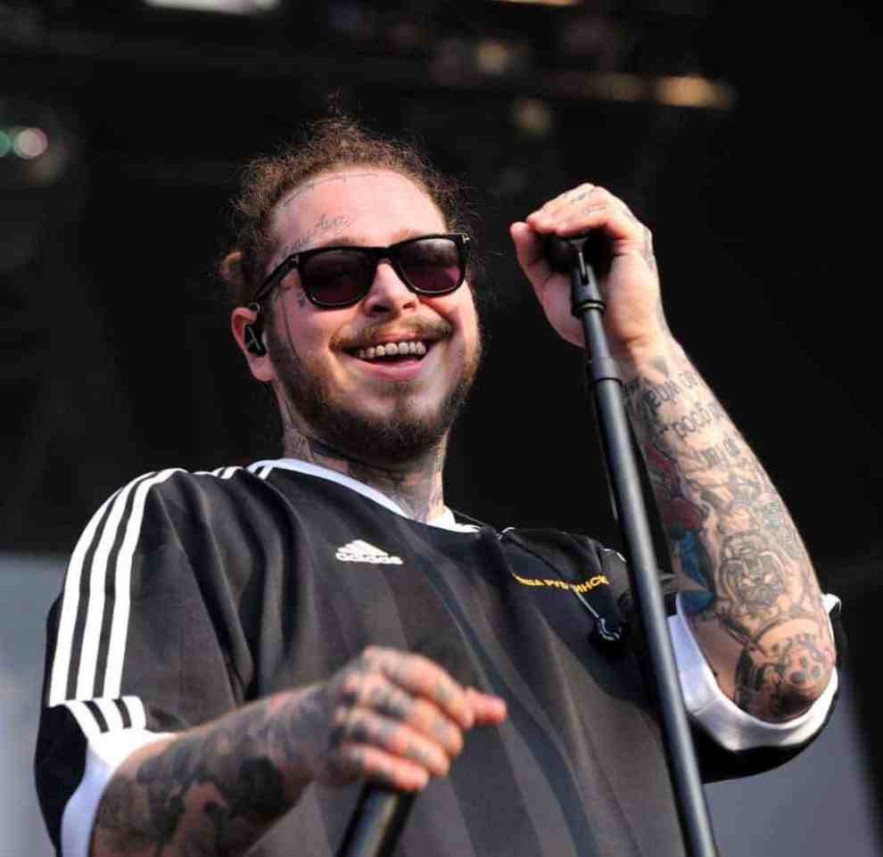 Post Malone wearing sunglasses and holding  a microphone