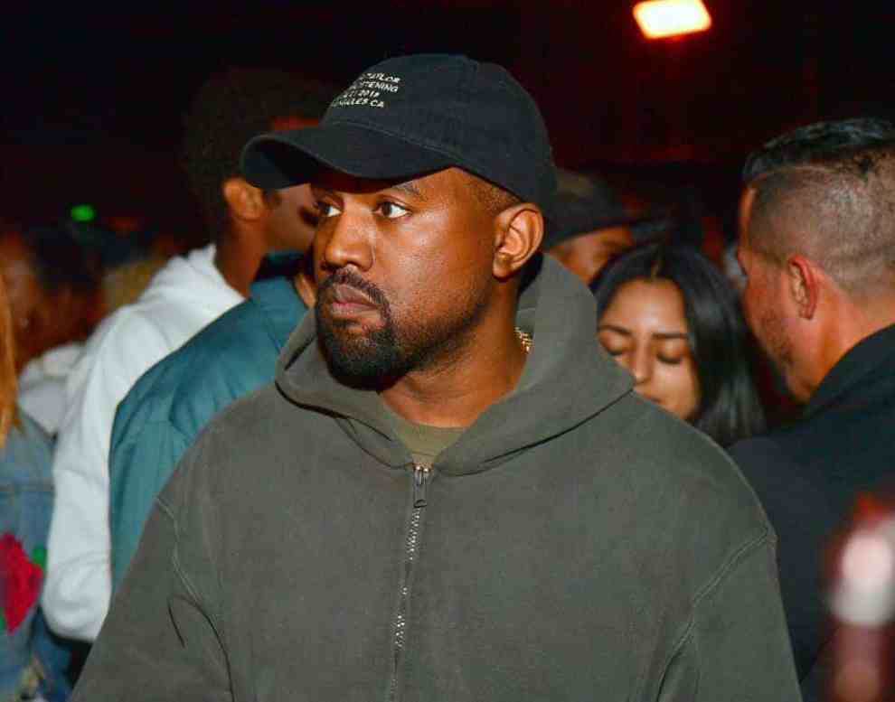 Kanye West in gray zip up sweatshirt and black baseball hat