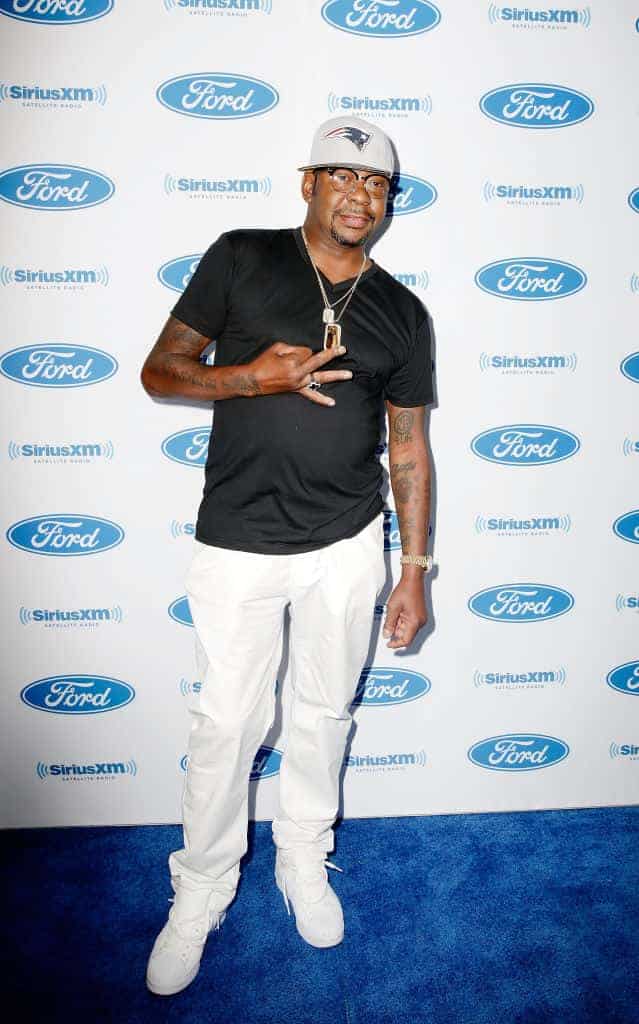 Bobby Brown wearing black and white standing in front of a white and blue backdrop