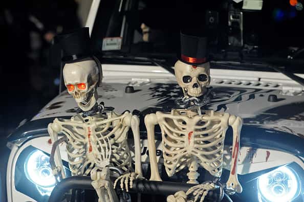 Halloween decorations of skeletons on front of a car