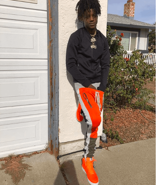 OMB Peezy standing up against a wall