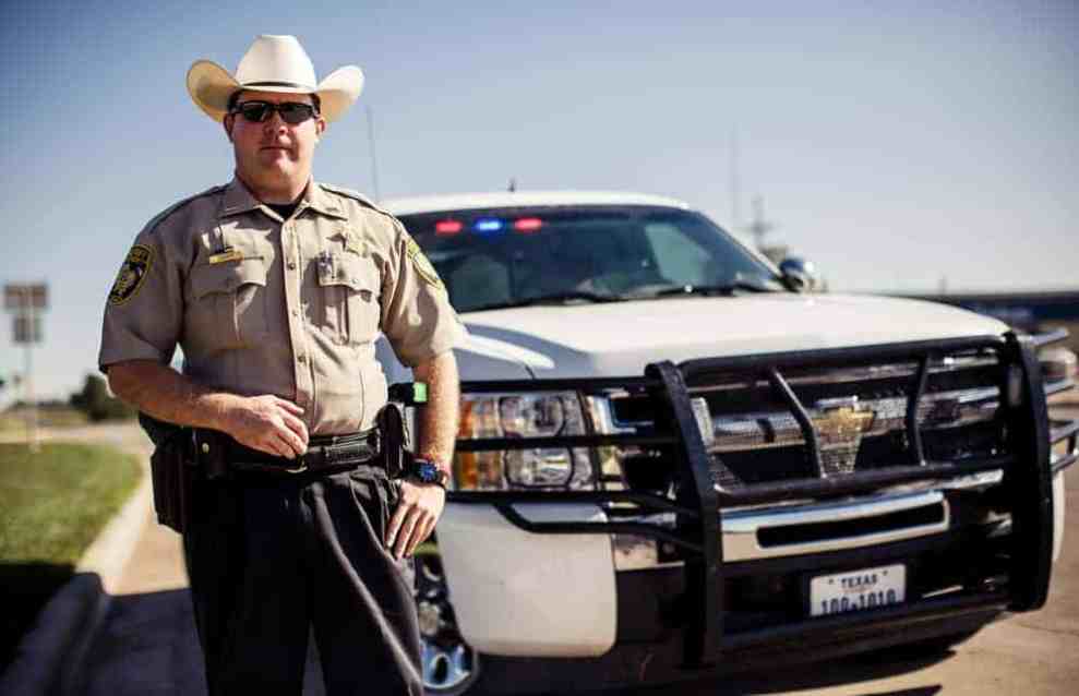 Texas police officer standing in front of his car