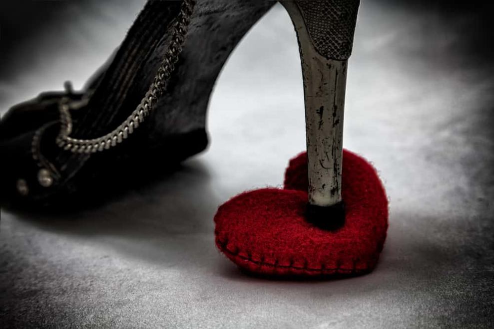 A black heel stepping on a red heart.