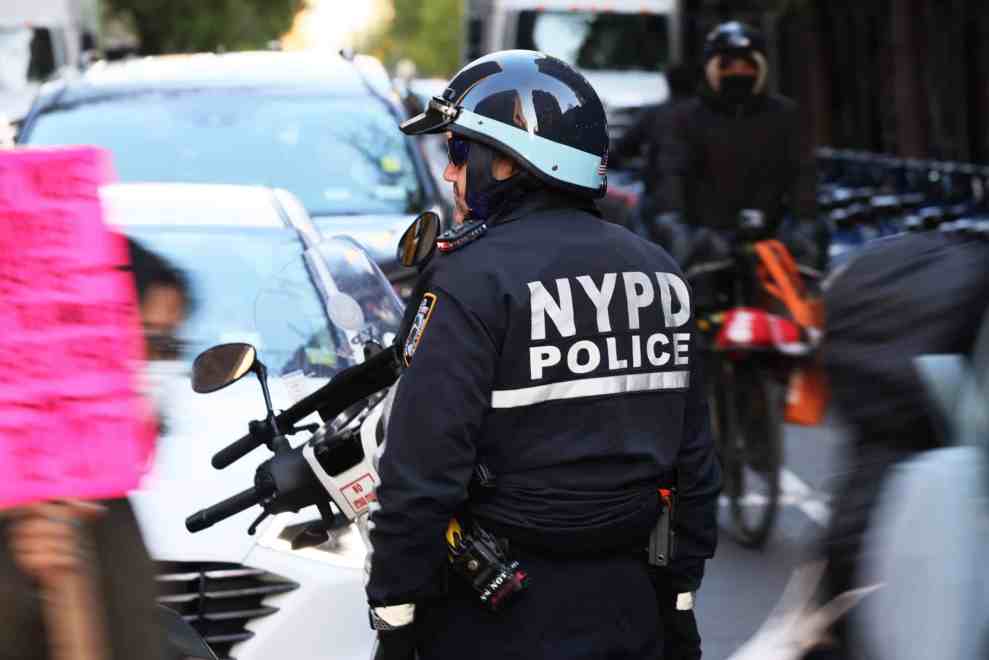 An NYPD officer blocks traffic as immigrant construction workers march as they observe Fallen Worker Day on April 28, 2022 in New York City. Immigrant construction workers were joined by city officials as they gathered at Union Square and then marched to Washington Square park to commemorate Fallen Worker Day organized by New Immigrant Community Empowerment (NICE).